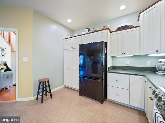 kitchen featuring dark countertops, range with gas cooktop, freestanding refrigerator, and recessed lighting
