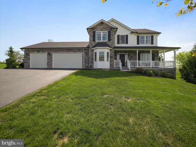 traditional home with a porch, driveway, a front yard, a garage, and stone siding