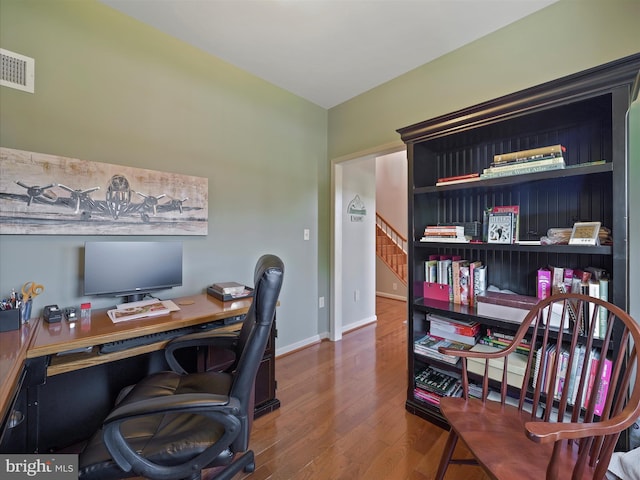 office area featuring baseboards, visible vents, and wood finished floors