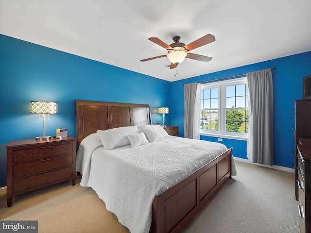 bedroom featuring light colored carpet, a ceiling fan, and baseboards