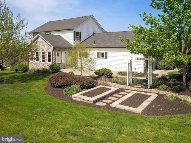 rear view of property featuring a lawn, a shingled roof, and stone siding