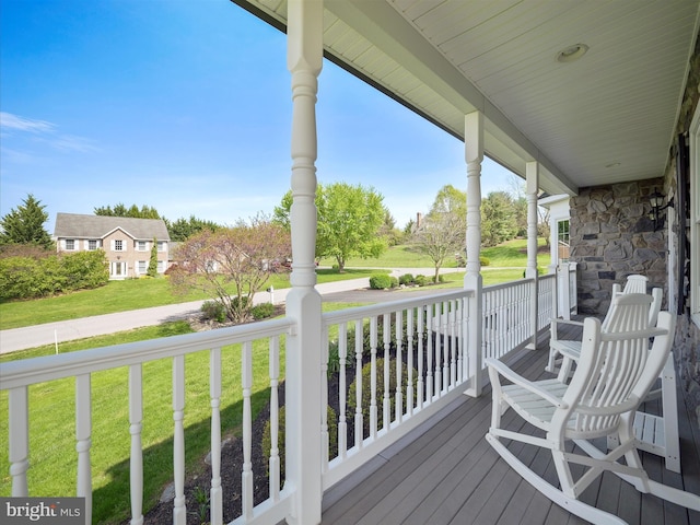 wooden deck featuring covered porch and a lawn