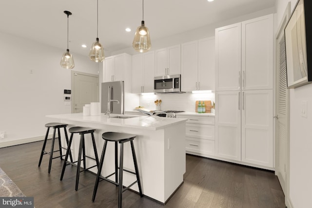 770 Park Rd NW Unit 201, Washington, DC 20010 - kitchen featuring appliances with stainless steel finishes, a center island with sink, backsplash, white cabinetry, and dark wood finished floors