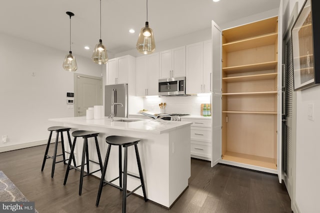 770 Park Rd NW Unit 201, Washington, DC 20010 - kitchen featuring appliances with stainless steel finishes, backsplash, dark wood finished floors, an island with sink, and white cabinetry
