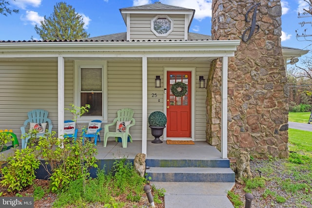 doorway to property featuring roof with shingles and covered porch