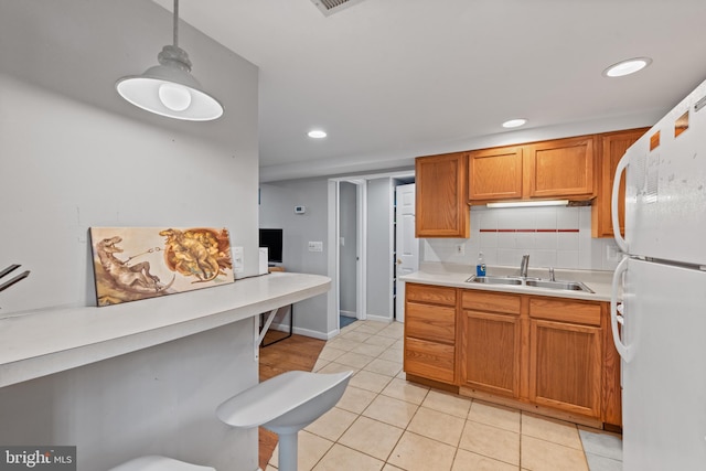 kitchen with a sink, light countertops, freestanding refrigerator, recessed lighting, and light tile patterned floors