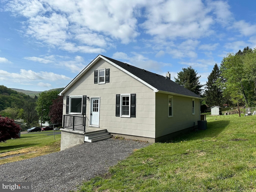 bungalow-style home with an outbuilding, central AC, a storage shed, and a front yard