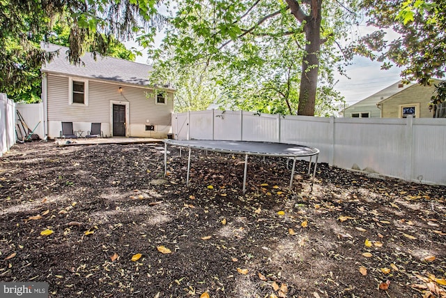 103 Dunn Ln, Pennsville, NJ 08070 - back of house featuring a fenced backyard, a trampoline, and a shingled roof