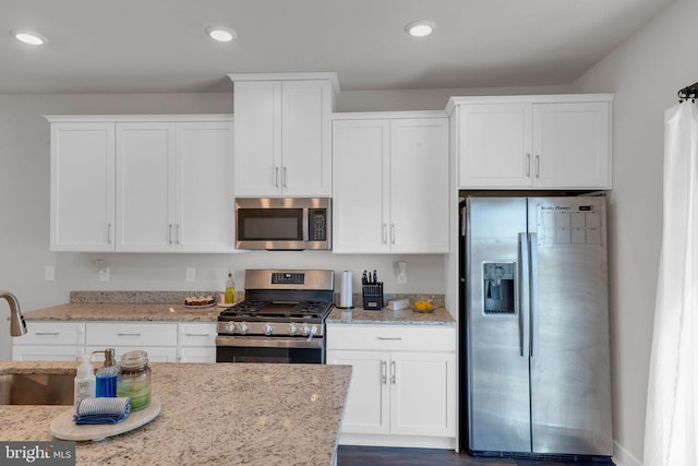 kitchen with light stone counters, stainless steel appliances, recessed lighting, and white cabinetry
