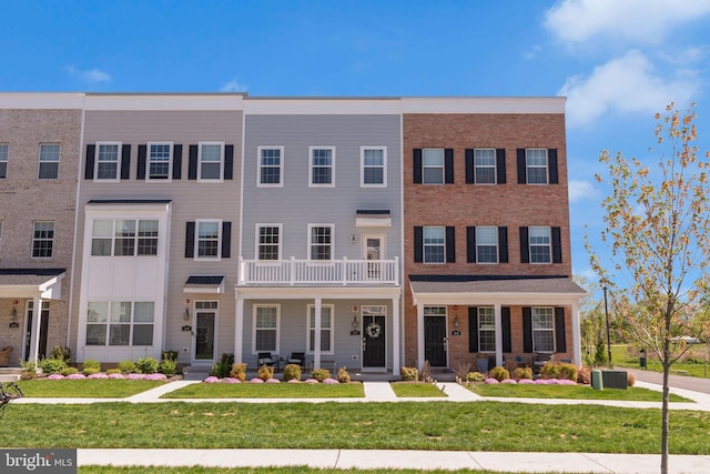townhome / multi-family property featuring a porch, brick siding, and a front yard