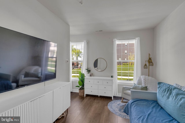 living area with baseboards, visible vents, a wealth of natural light, and dark wood finished floors