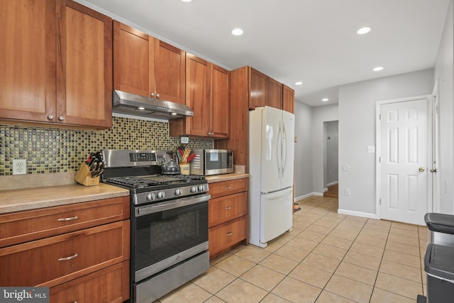 kitchen featuring light countertops, appliances with stainless steel finishes, under cabinet range hood, and tasteful backsplash