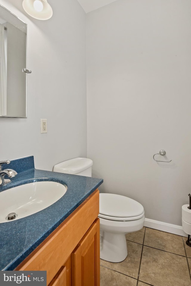 half bath featuring vanity, tile patterned flooring, baseboards, and toilet