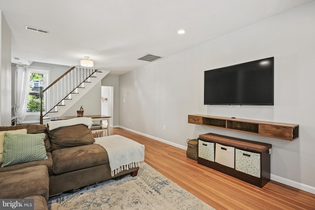 living area featuring visible vents, baseboards, wood finished floors, and stairway