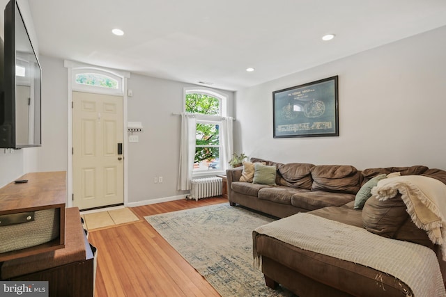living room featuring recessed lighting, baseboards, radiator, and wood finished floors