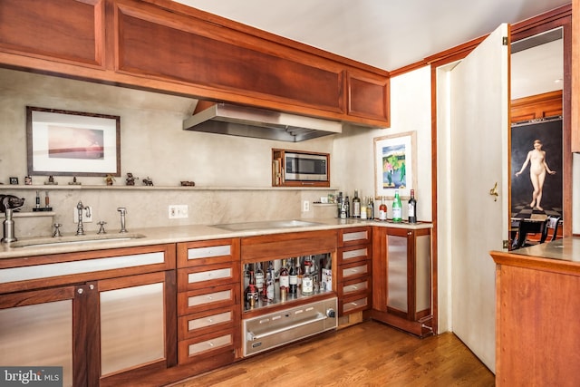 2740 Chain Bridge Rd NW, Washington, DC 20016 - bar featuring light wood-style flooring, stainless steel microwave, a sink, wet bar, and wall chimney range hood