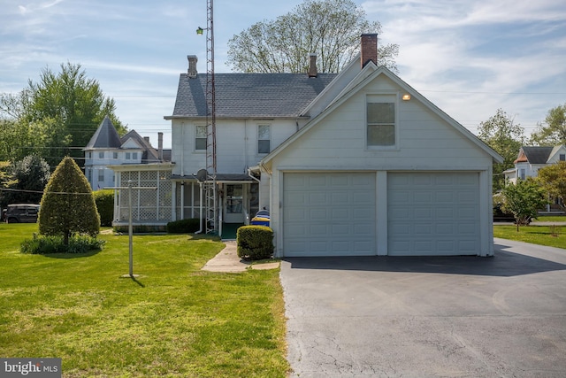 back of house with a yard, a chimney, roof with shingles, and a garage