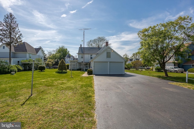 view of front of home with a detached garage, fence, a front lawn, and a residential view