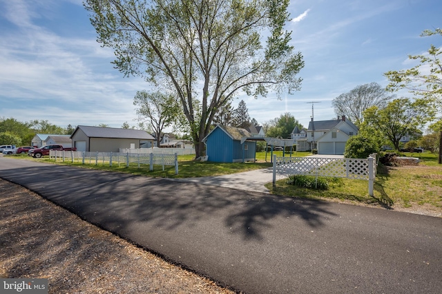 view of front of property featuring fence, a garage, driveway, and a residential view
