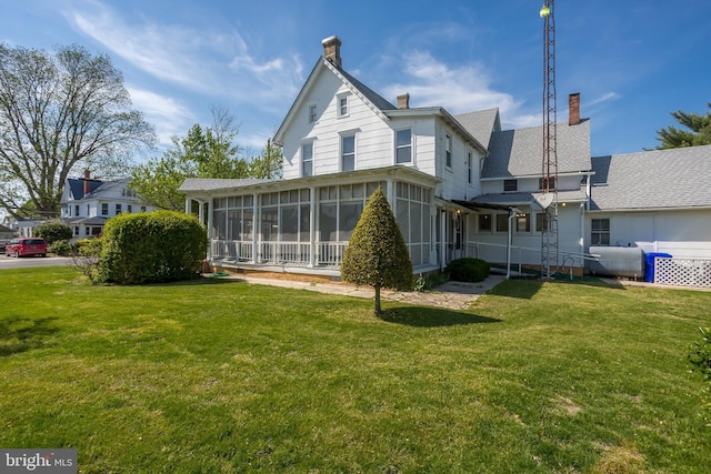 back of house with a yard, heating fuel, a chimney, and a sunroom