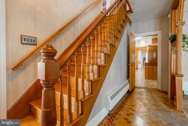 stairs with wallpapered walls and radiator heating unit