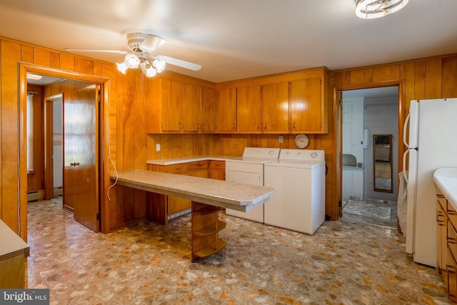 kitchen featuring independent washer and dryer, brown cabinets, light countertops, wood walls, and freestanding refrigerator