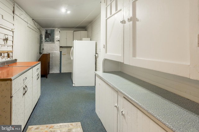 kitchen featuring freestanding refrigerator, white cabinetry, light countertops, and dark colored carpet