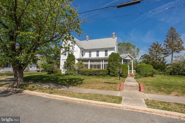 traditional home featuring a chimney and a front yard