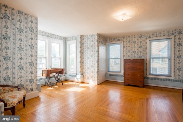 living area featuring baseboards, radiator, and wallpapered walls