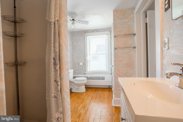 bathroom with vanity, wood finished floors, toilet, a shower with shower curtain, and a ceiling fan