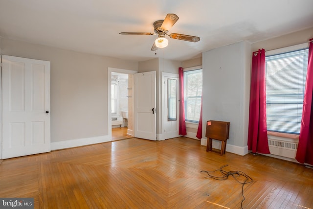unfurnished bedroom featuring baseboards, ceiling fan, ensuite bath, and radiator