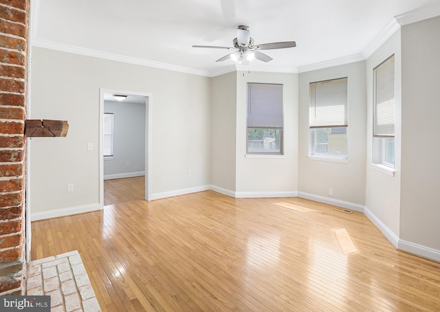 empty room with baseboards, ceiling fan, light wood finished floors, and crown molding