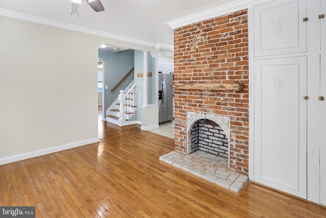unfurnished living room with ceiling fan, light wood-style floors, stairway, and ornamental molding