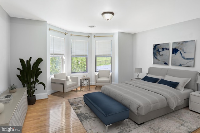 bedroom featuring baseboards, light wood-style floors, and visible vents