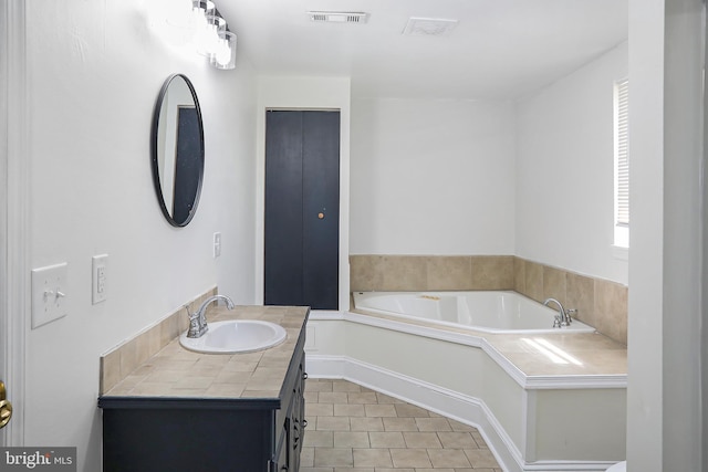 bathroom with vanity, tile patterned floors, a garden tub, and visible vents