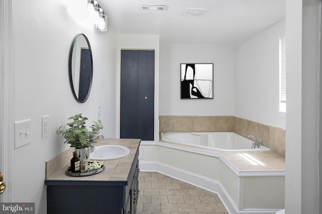 bathroom with tile patterned flooring, a garden tub, visible vents, and vanity
