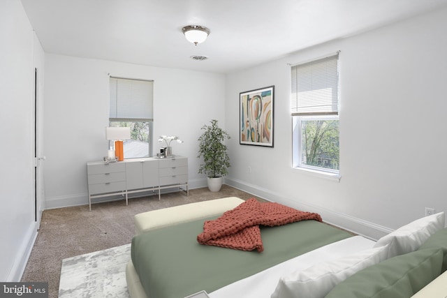 carpeted bedroom featuring multiple windows, visible vents, and baseboards