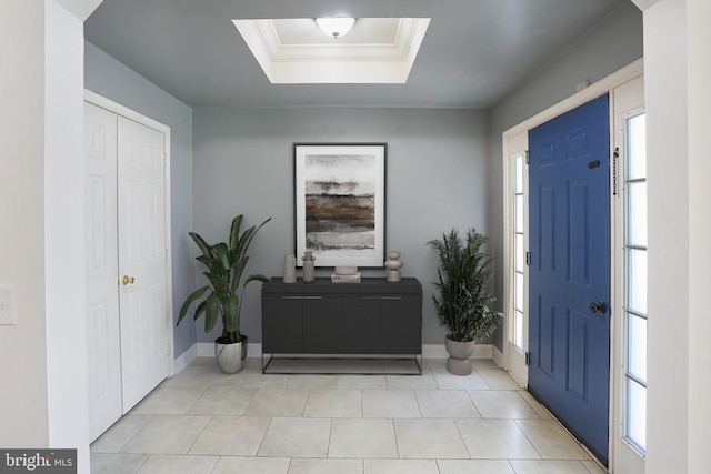 foyer entrance with light tile patterned floors, baseboards, a raised ceiling, and a healthy amount of sunlight