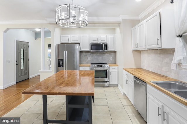 kitchen with wooden counters, stainless steel appliances, and white cabinets