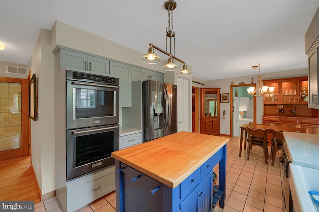 kitchen featuring visible vents, light tile patterned flooring, wooden counters, a chandelier, and appliances with stainless steel finishes