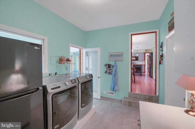 laundry area featuring baseboards, laundry area, visible vents, and washer and clothes dryer
