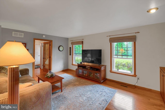 living area with visible vents, a healthy amount of sunlight, and hardwood / wood-style flooring