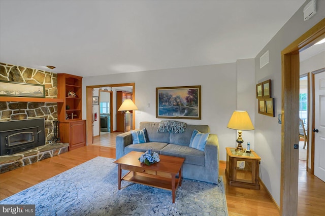 living area featuring visible vents, baseboards, wood finished floors, and a healthy amount of sunlight