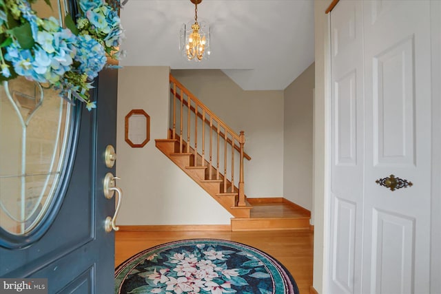 foyer featuring an inviting chandelier, stairs, and wood finished floors