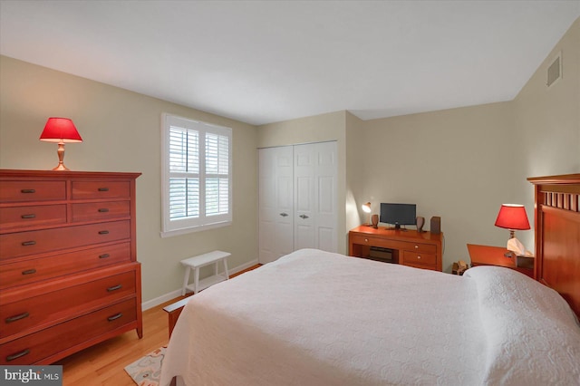 bedroom with light wood-style floors, baseboards, visible vents, and a closet