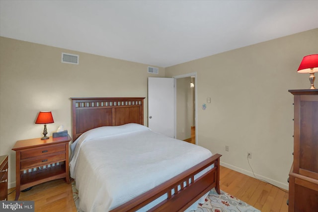 bedroom with baseboards, visible vents, and light wood-style floors