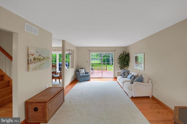 living area featuring stairs, baseboards, visible vents, and light wood-style floors