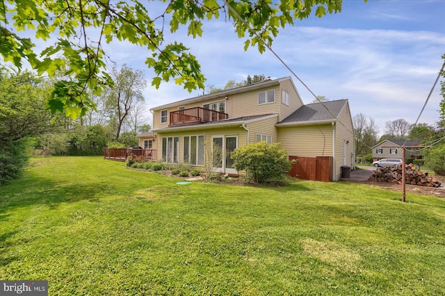 back of house featuring a yard, a deck, and a balcony