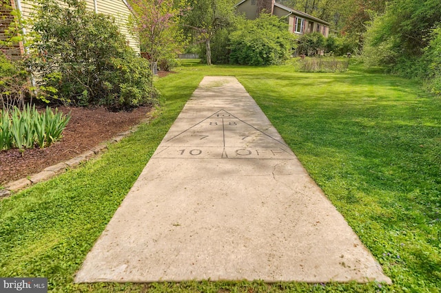 view of community with a yard and shuffleboard