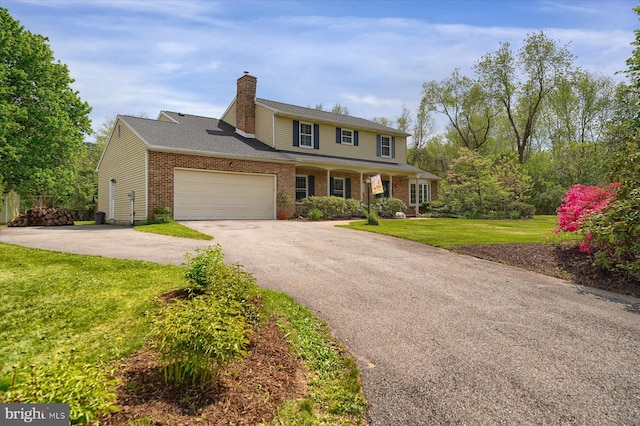 view of front of house with a front lawn, aphalt driveway, a chimney, brick siding, and an attached garage